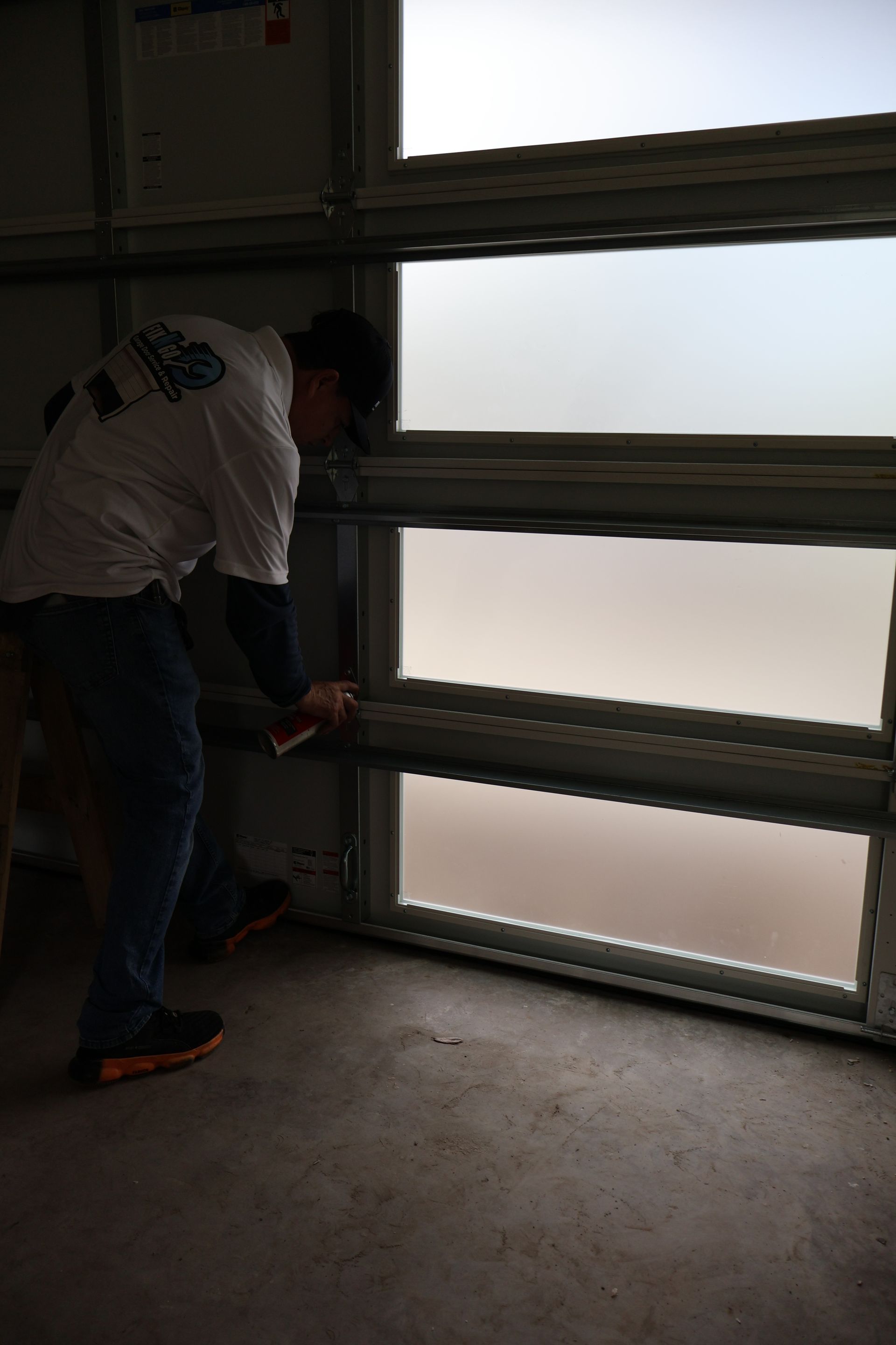 Person adjusting a metal garage door in a dim room