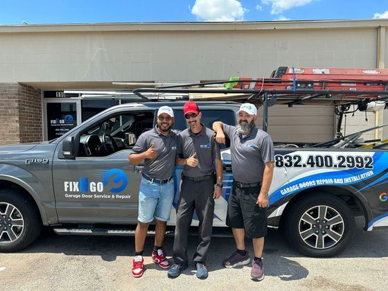 Three workers posing in front of a blue-and-black service truck outside a building