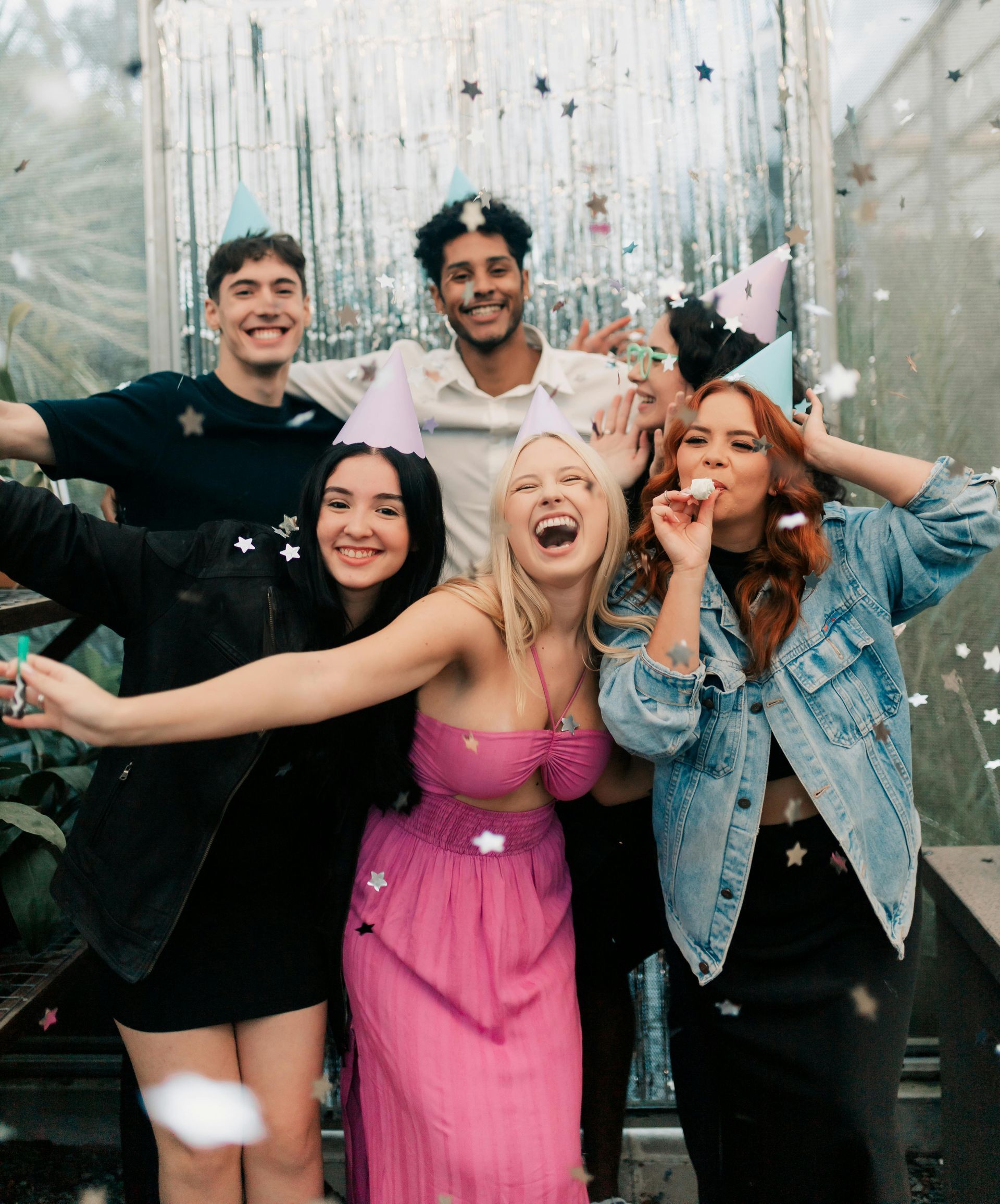 Group of people celebrating with party hats and confetti.