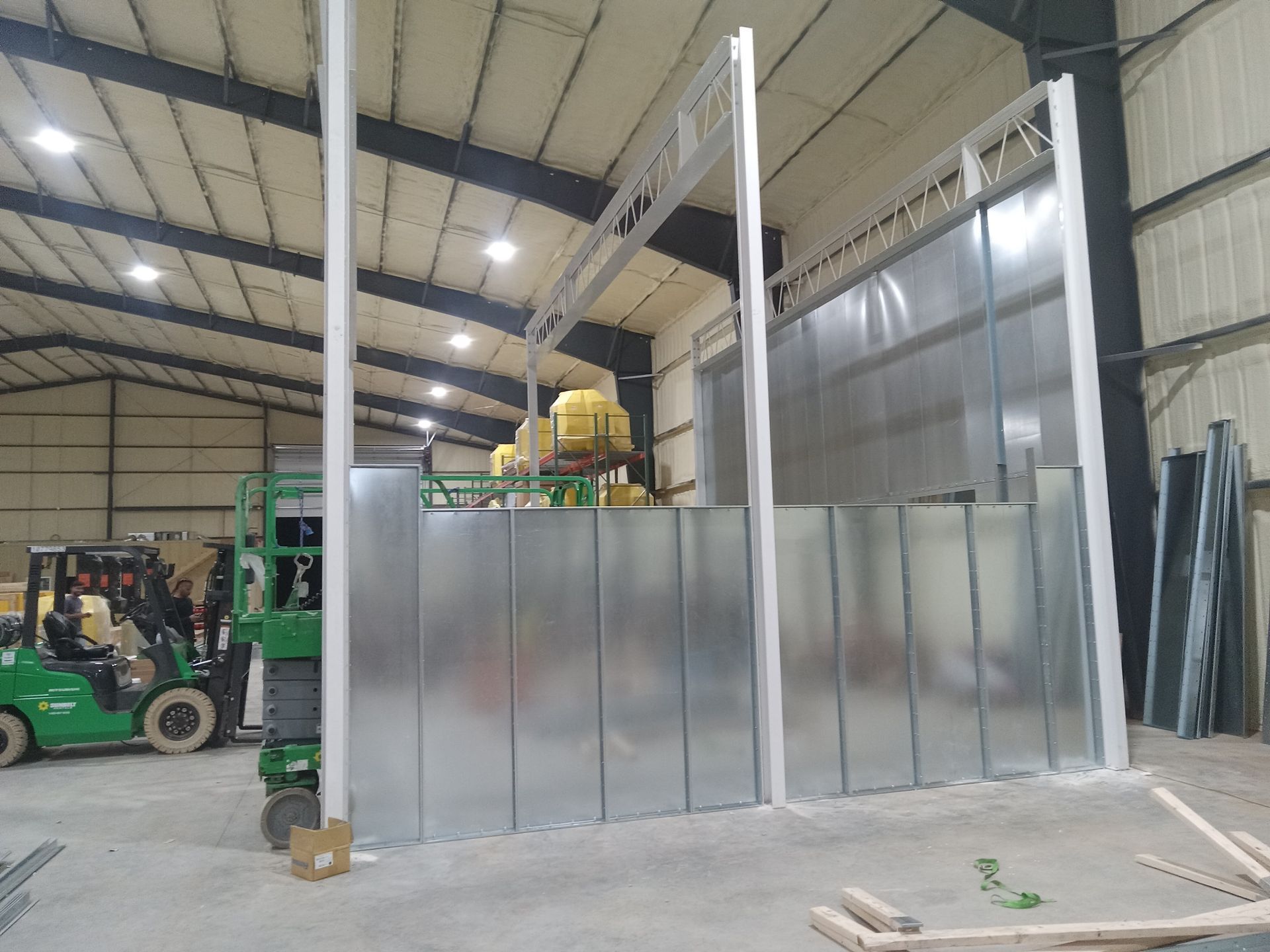A green forklift is driving through a large warehouse.