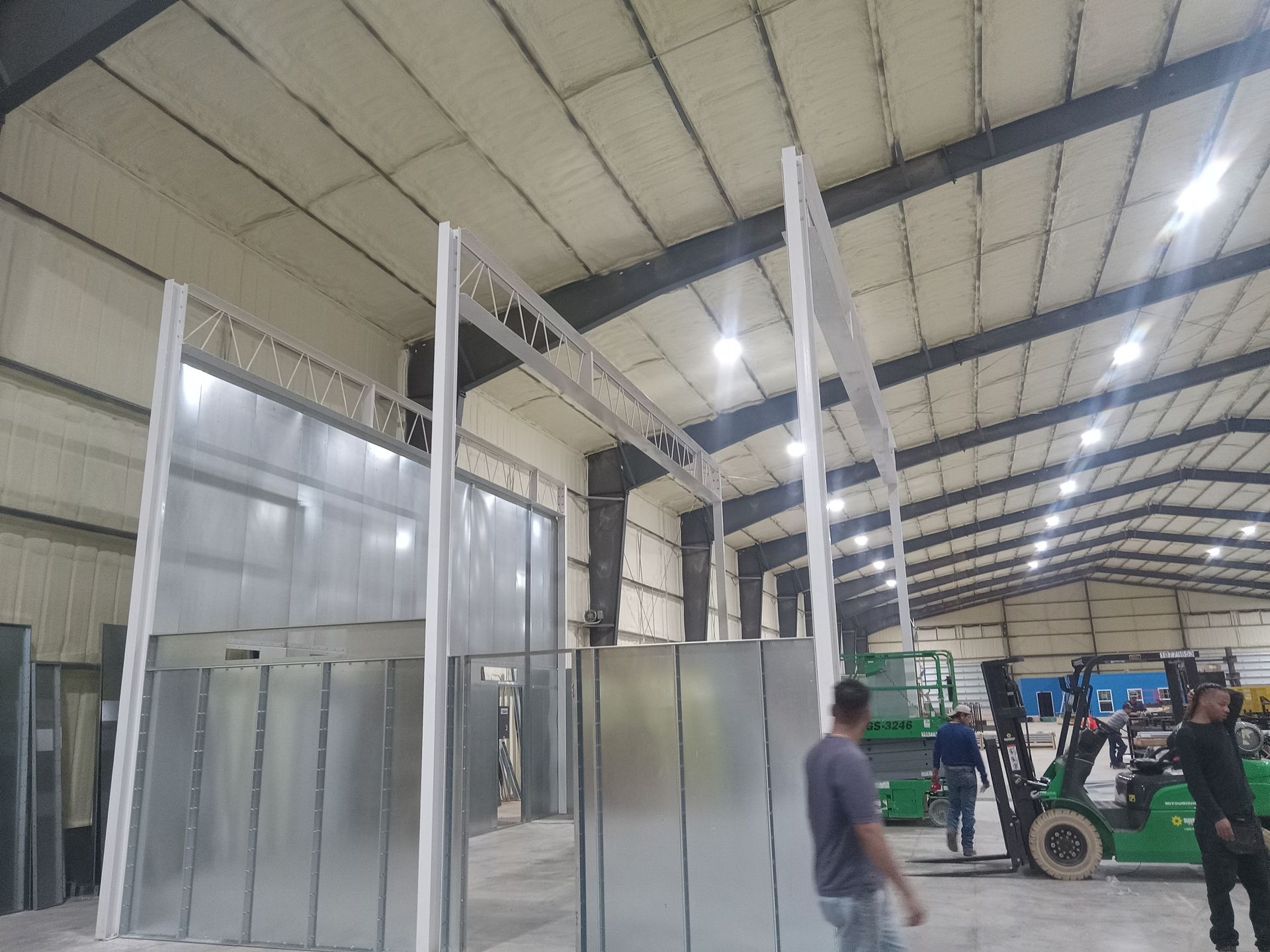 A man is standing in a large warehouse next to a forklift.