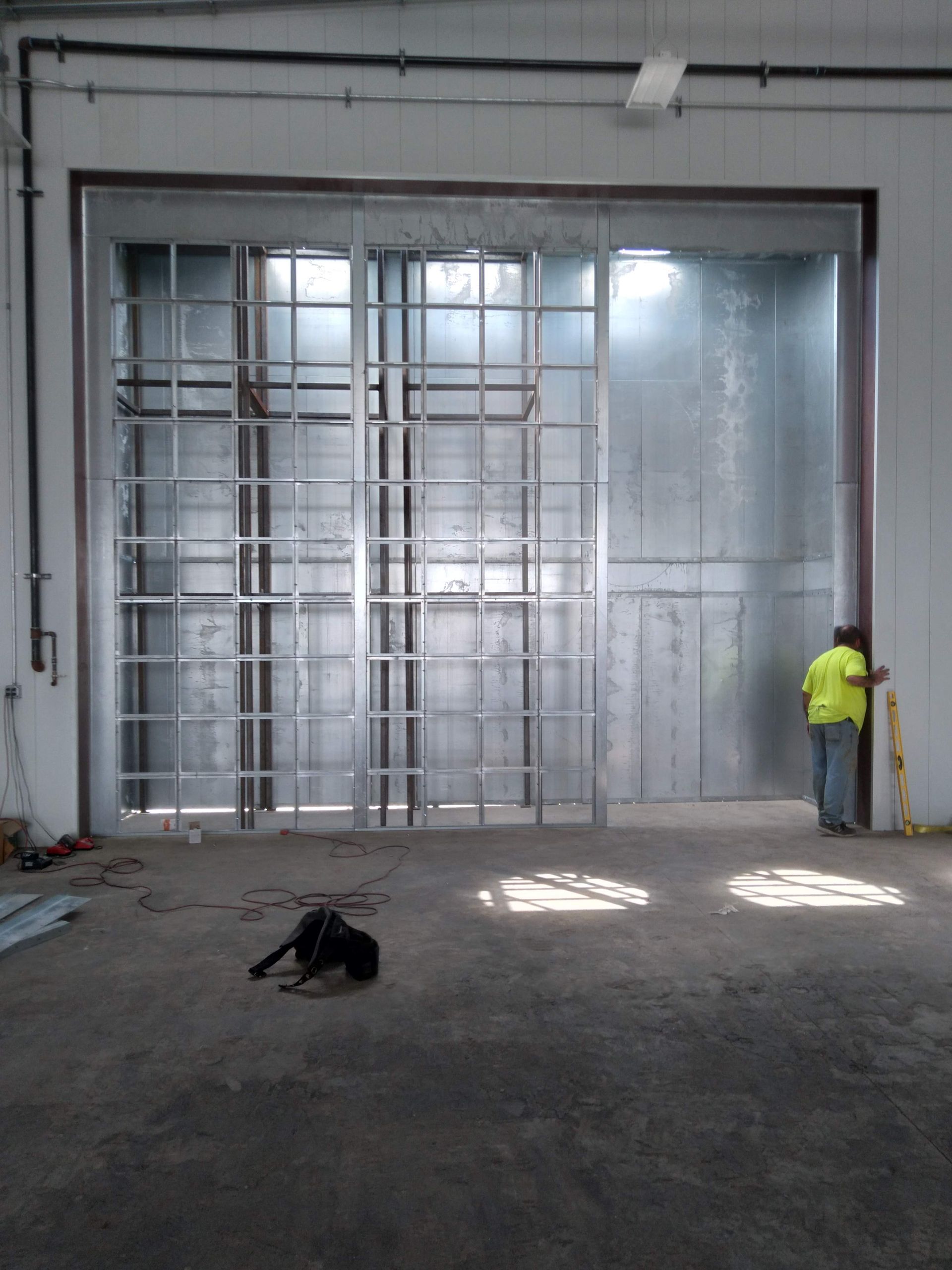 A man in a yellow shirt is standing in front of a large metal door