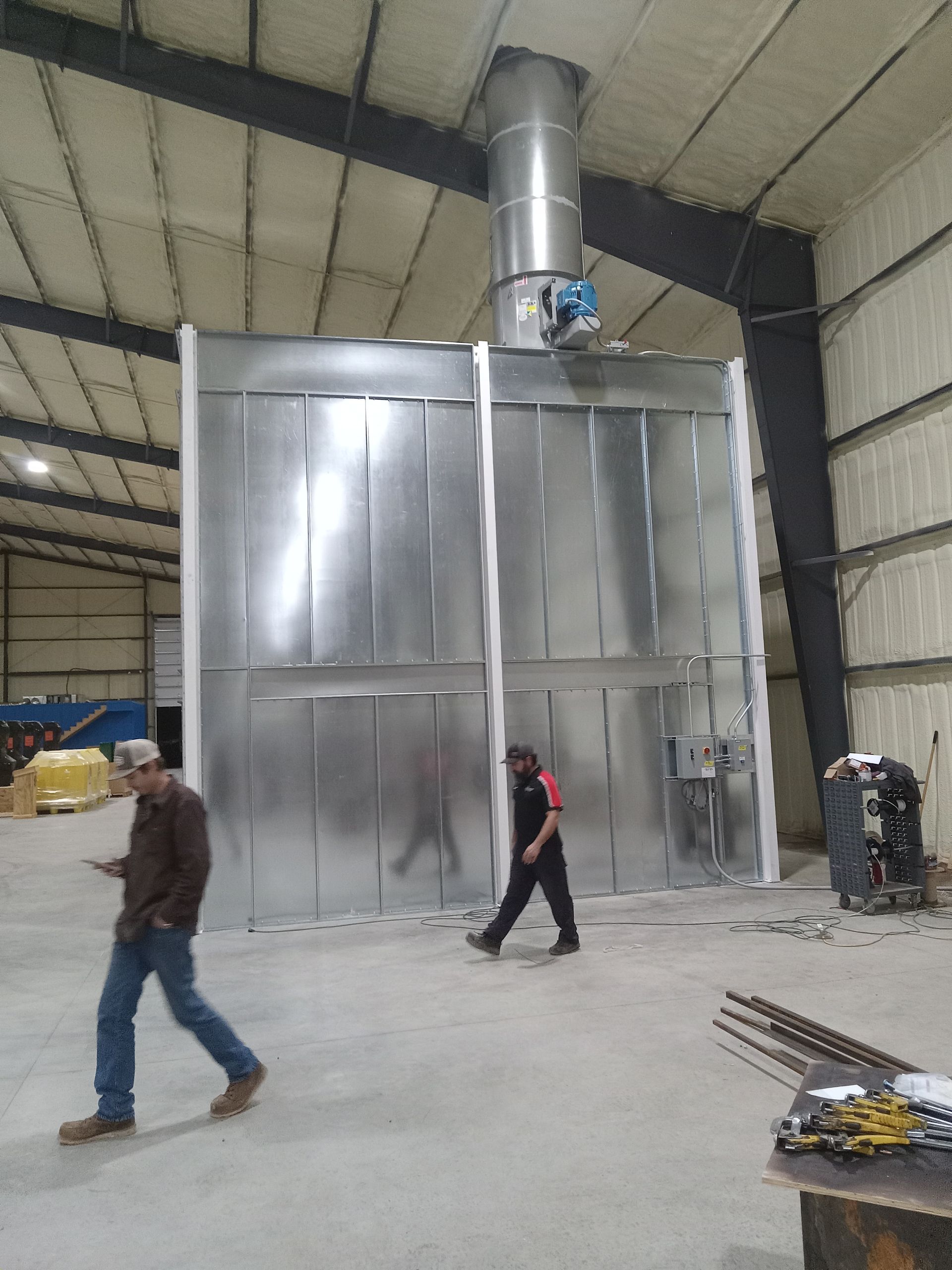 A man is walking in front of a metal wall in a warehouse
