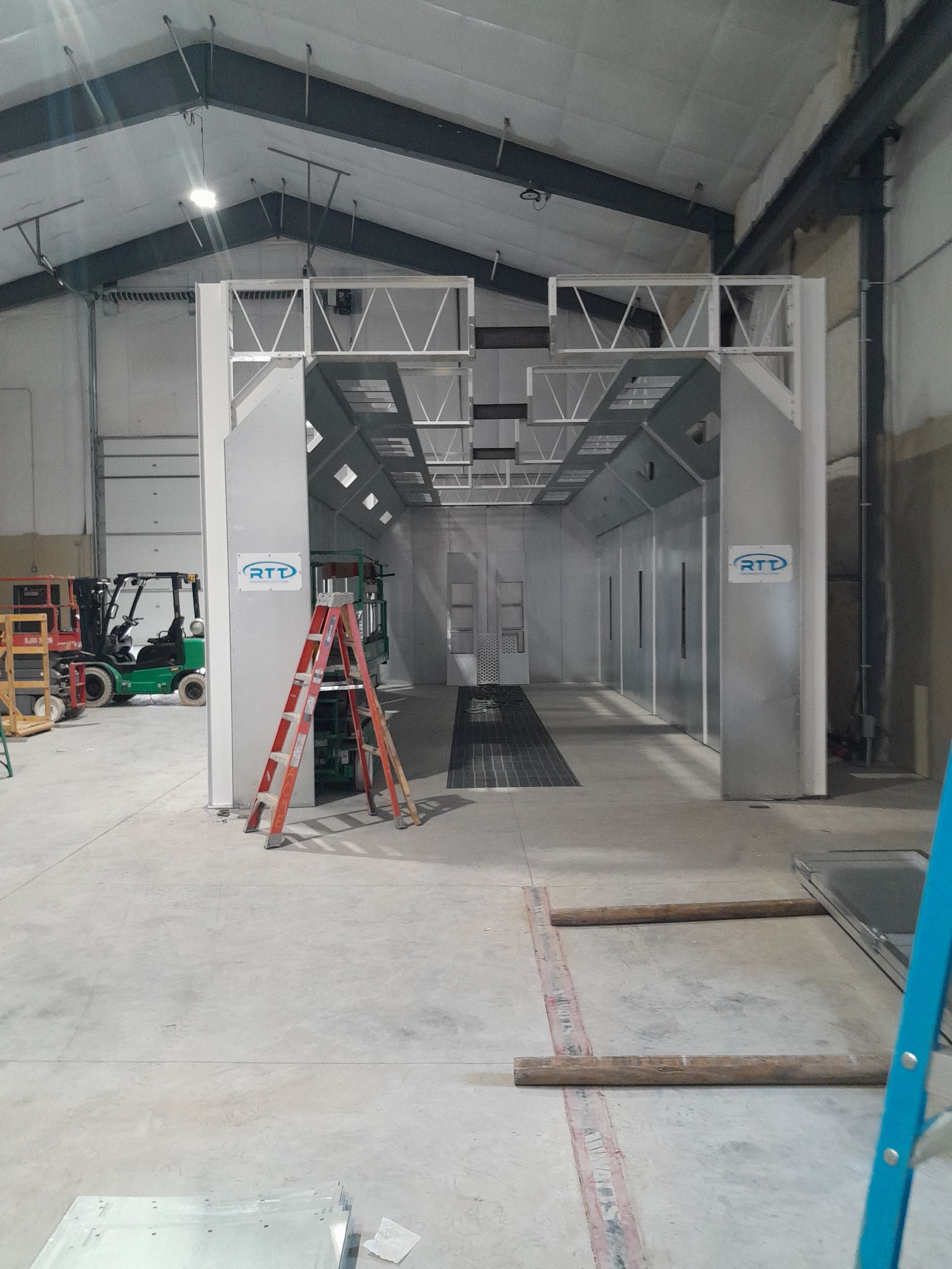 A large warehouse with a forklift in the background and a ladder in the foreground.