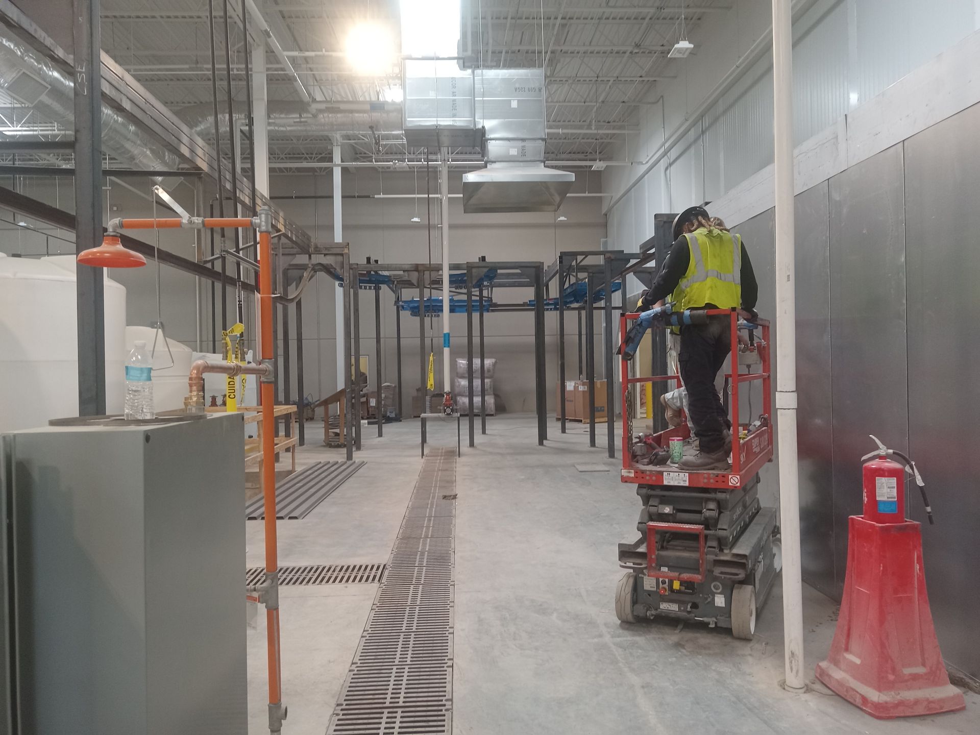 A man is standing on a scissor lift in a large warehouse.