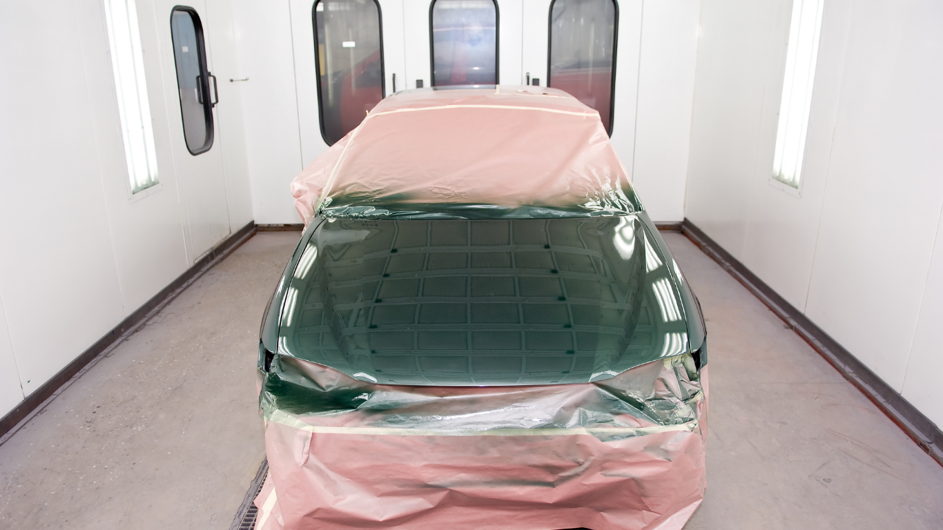 A car is wrapped in plastic in a paint booth.
