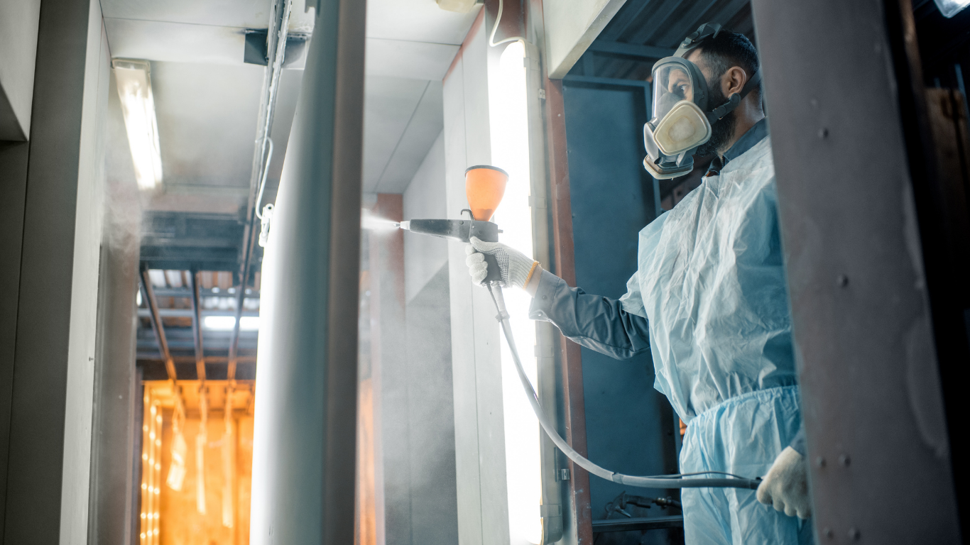 A man wearing a gas mask is spraying paint on a wall.