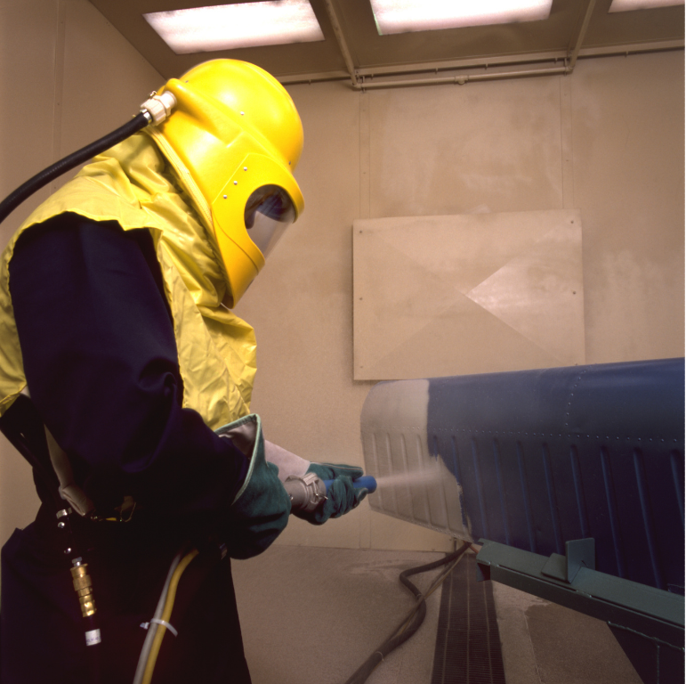 A man wearing a yellow helmet is spraying something
