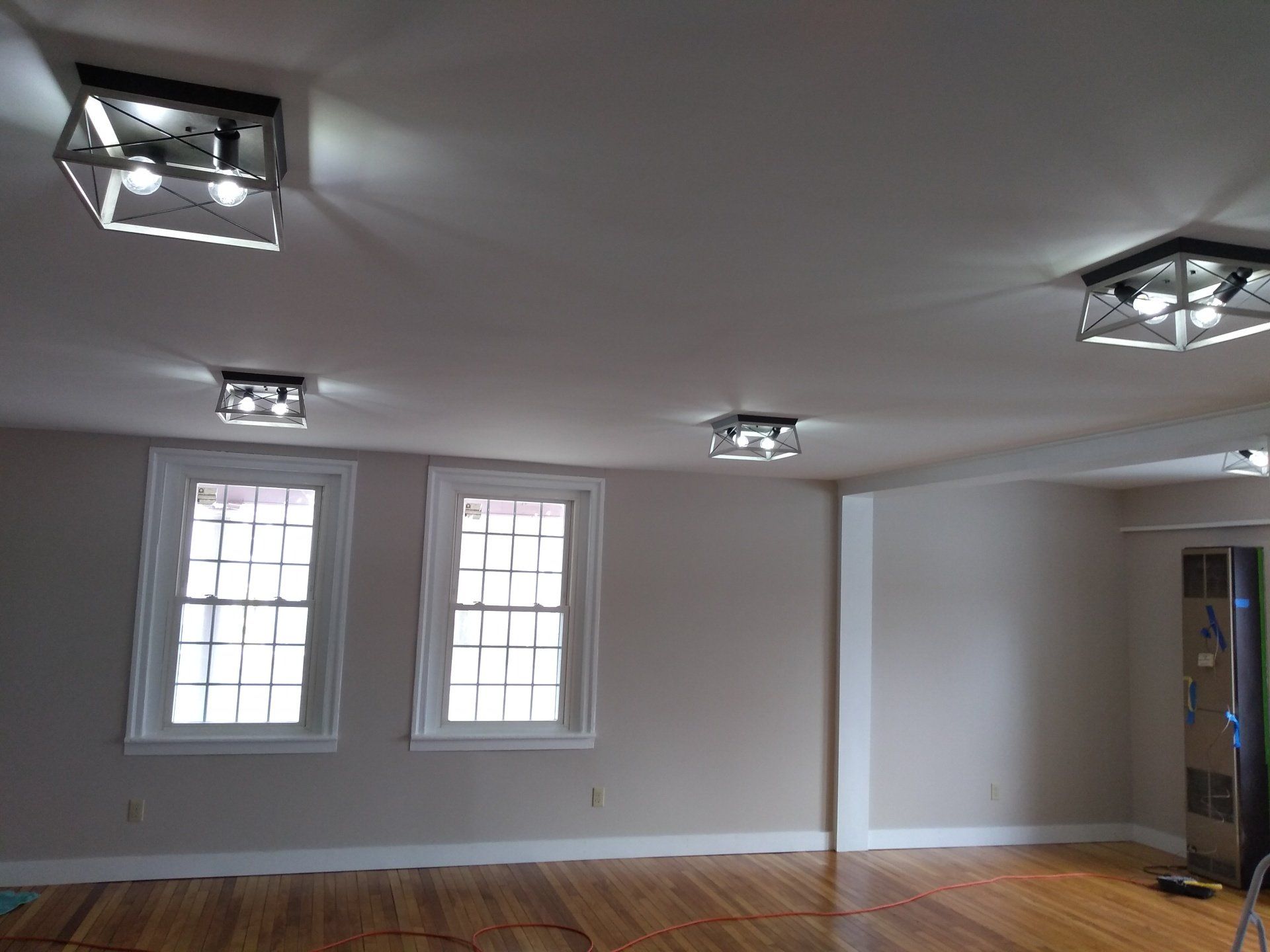 a white room with hardwood floors and ceiling lights.