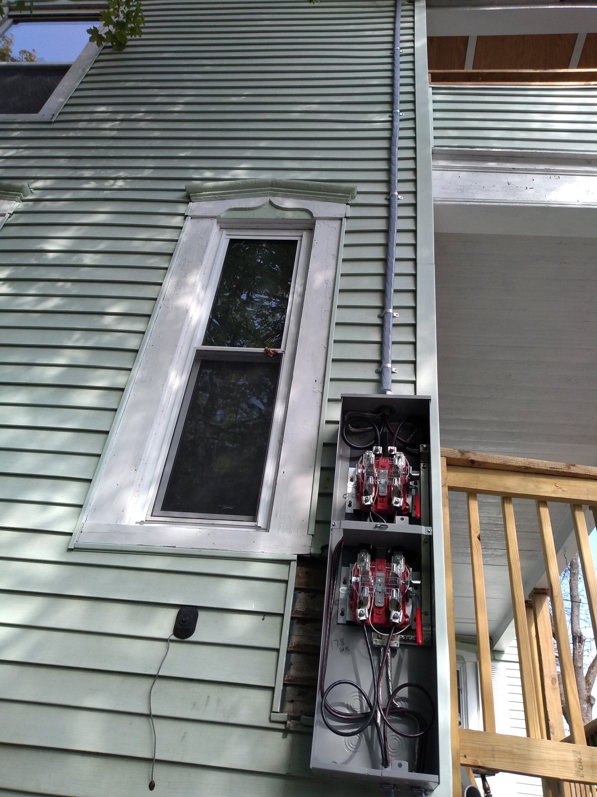 a house with a window and an electrical box mounted on the side of it