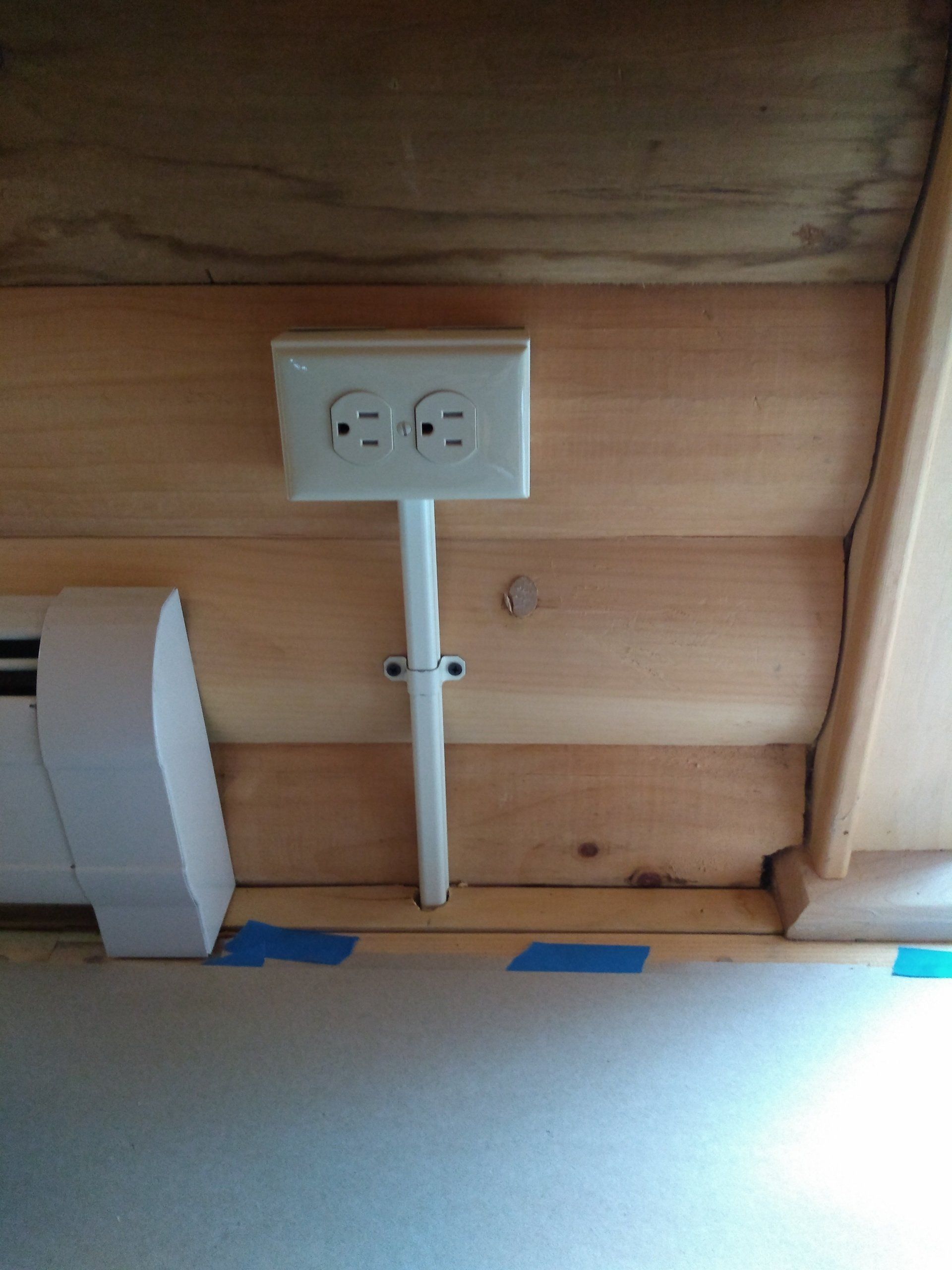 a white electrical outlet attached to a wooden wall .