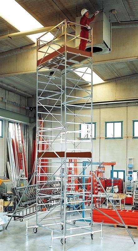 Un uomo è in piedi su un'impalcatura in un magazzino.