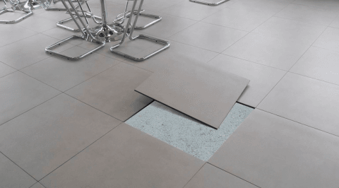 Un pavimento piastrellato con un buco e un tavolo sullo sfondo.