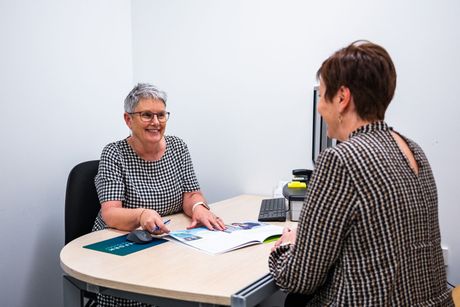 Two women are sitting at a table talking to each other