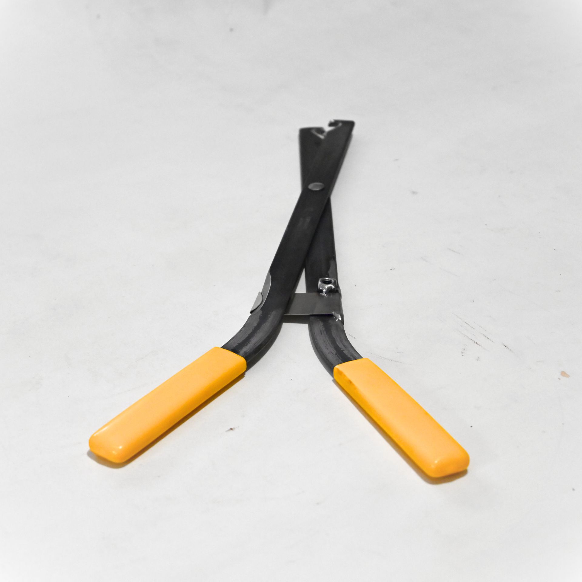 Pince noire et jaune sur une surface blanche.