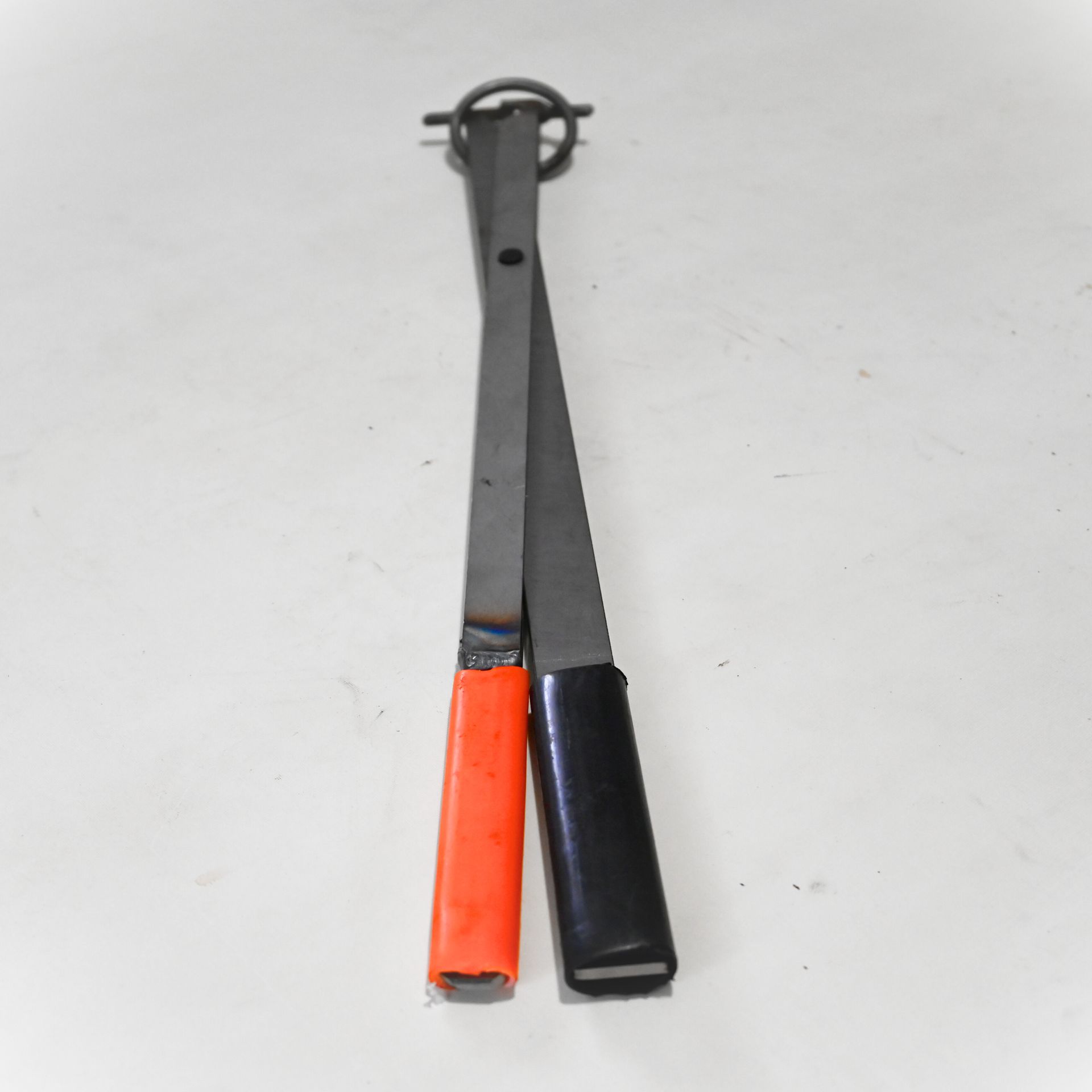 Deux outils à main en métal, l'un avec des manches orange et l'autre avec des manches noirs, reliés par un anneau.