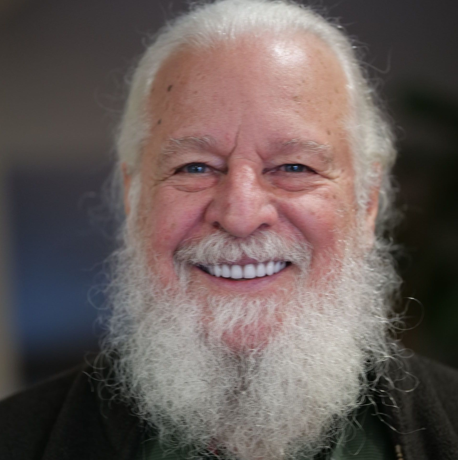 Homme souriant à la longue barbe et aux cheveux blancs ; gros plan.