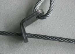 Gros plan sur un support métallique fixant une boucle d'un câble en acier à un autre morceau de câble en acier.