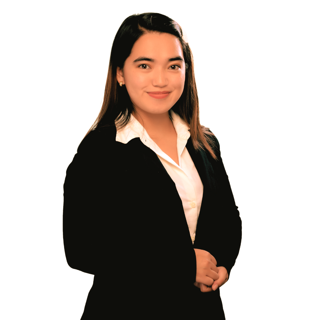A person with long, dark hair wearing a black blazer over a white collared shirt, posing against a white background.