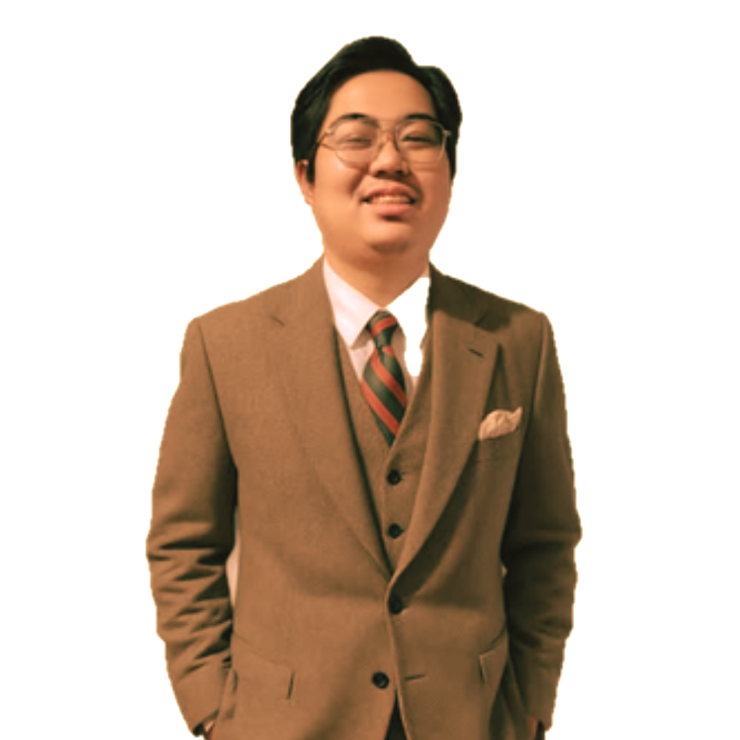 A smiling person wearing a brown three-piece suit, a white dress shirt, and a striped tie, standing against a white background.