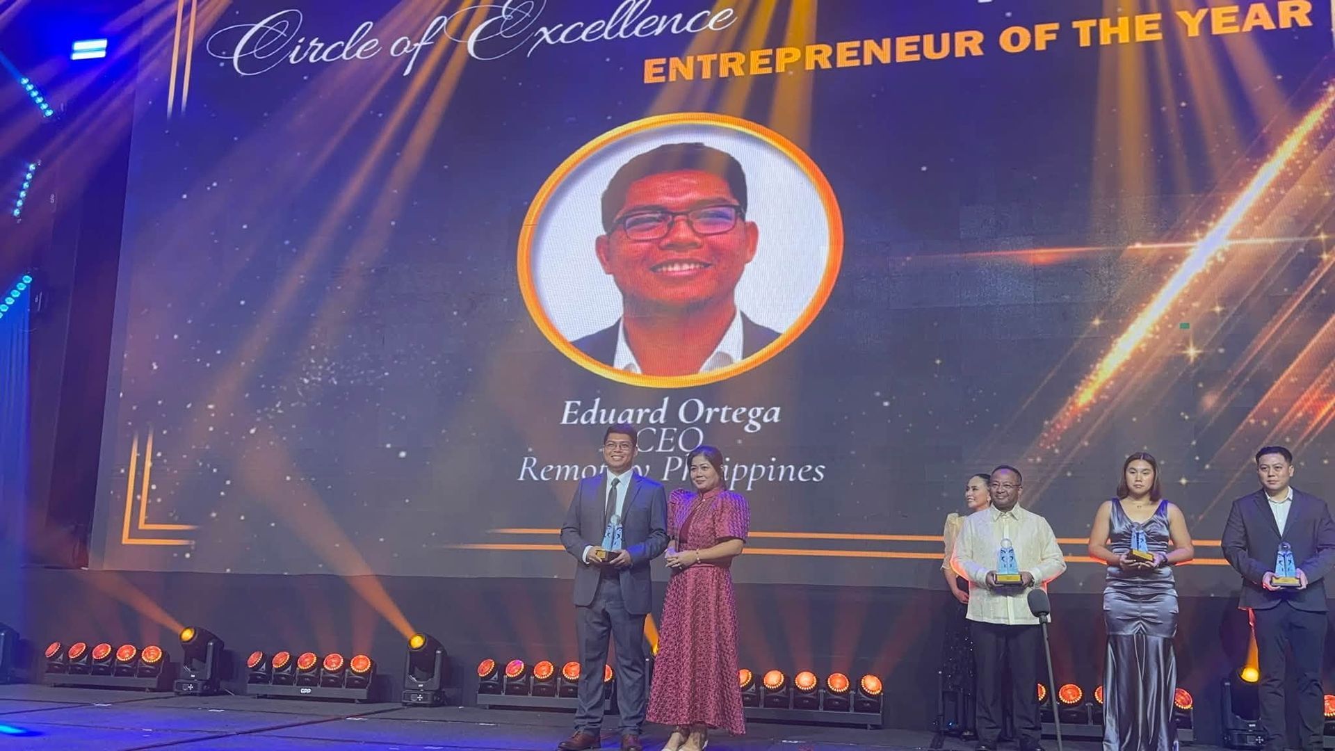 Award ceremony stage with large screen reading “Entrepreneur of the Year” and Eduard Ortega accepting the award