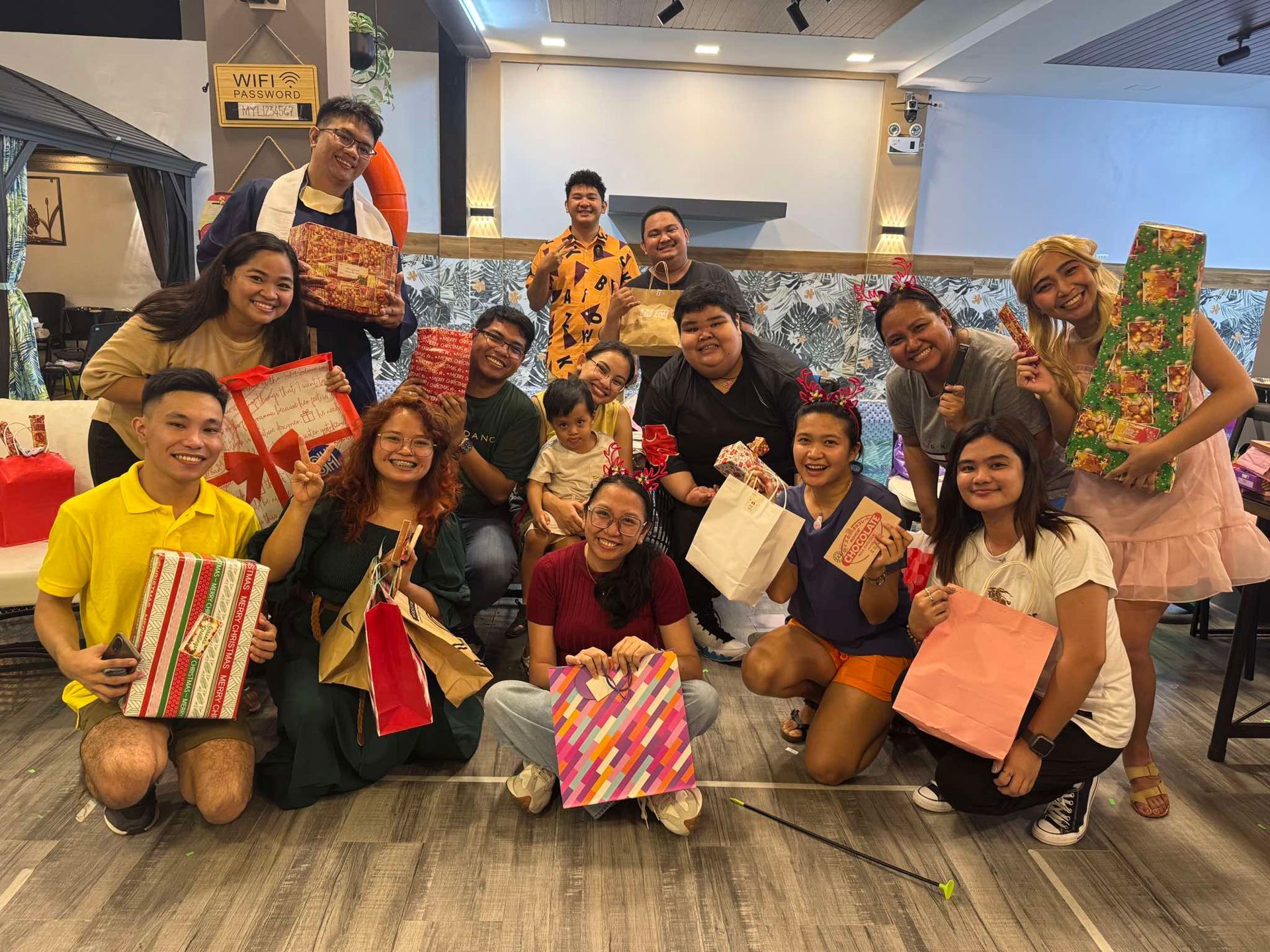 A group of people are posing for a picture while holding presents.