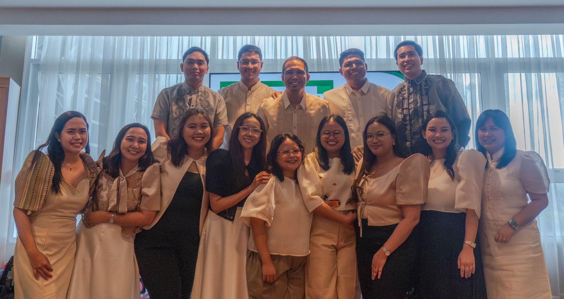 Group of people posing in formal attire indoors, smiling for a group photo.