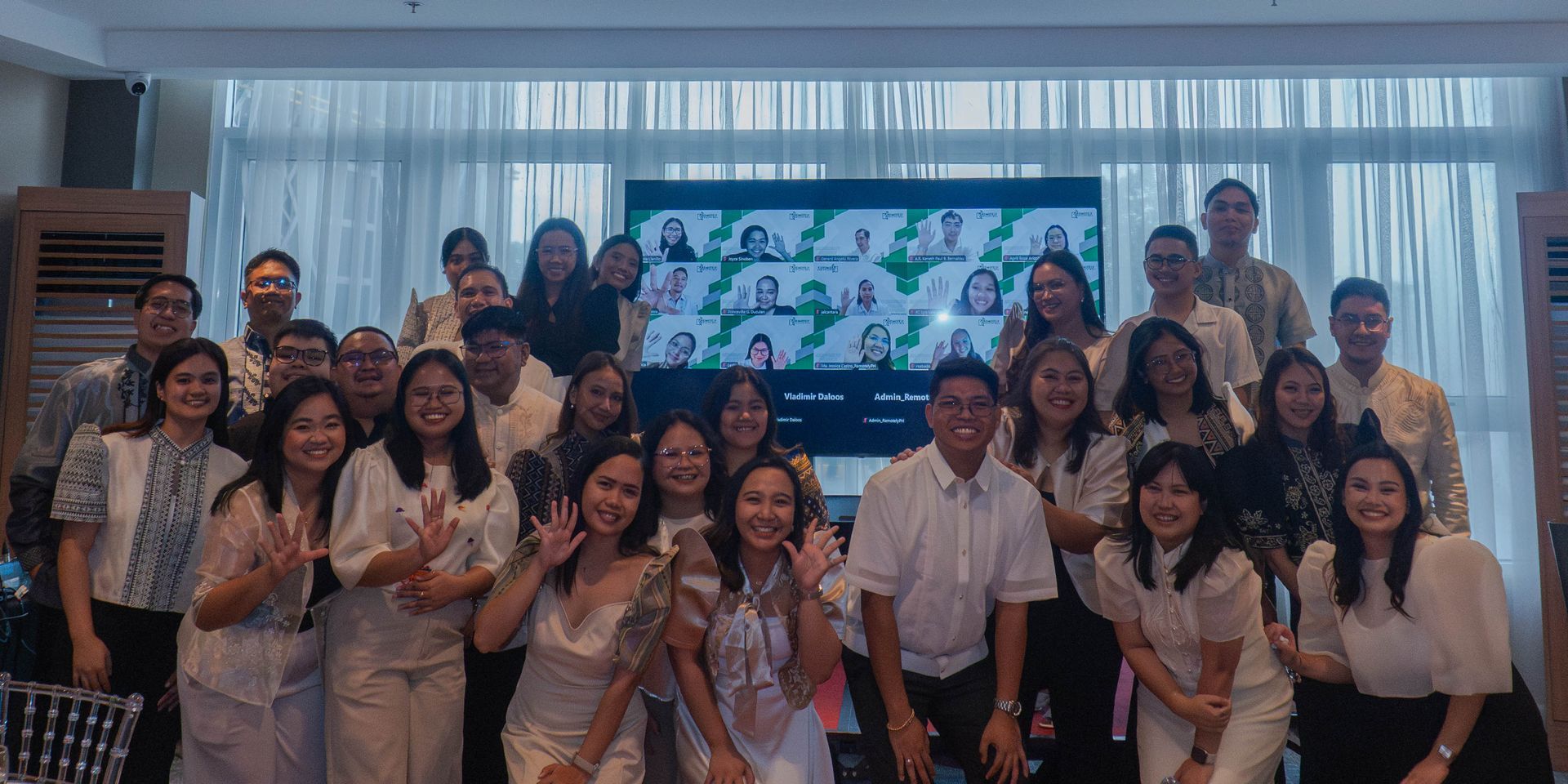 Group of people posing in a conference room, smiling in front of a large presentation screen