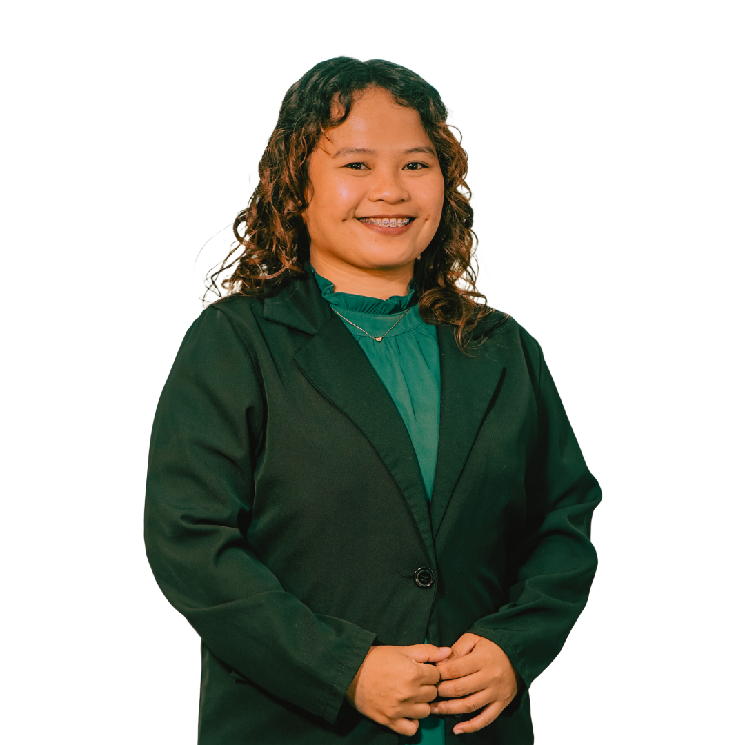 A smiling individual wearing a dark green blazer over a matching green high-neck top, posed against a white background.