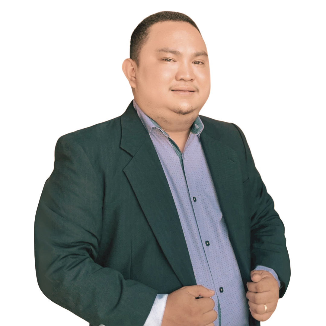 A person wearing a dark green blazer and light blue button-down shirt stands against a white background.