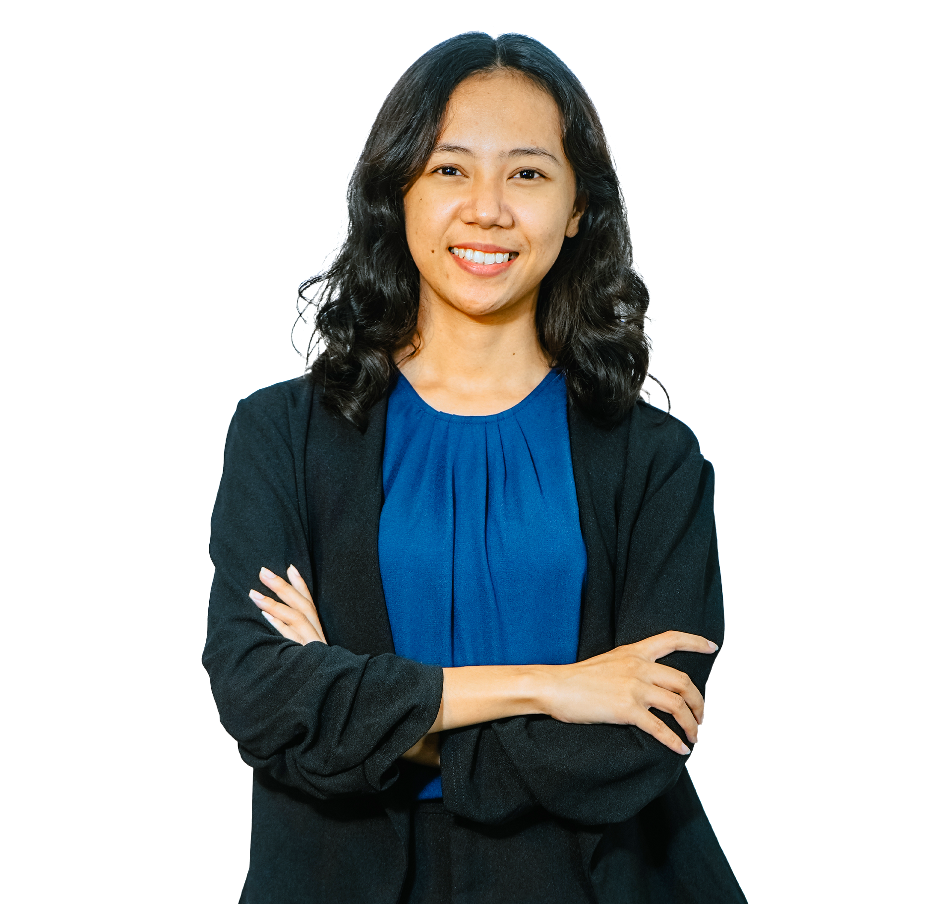 A smiling individual with dark wavy hair stands with arms crossed, wearing a dark green top under a black cardigan.