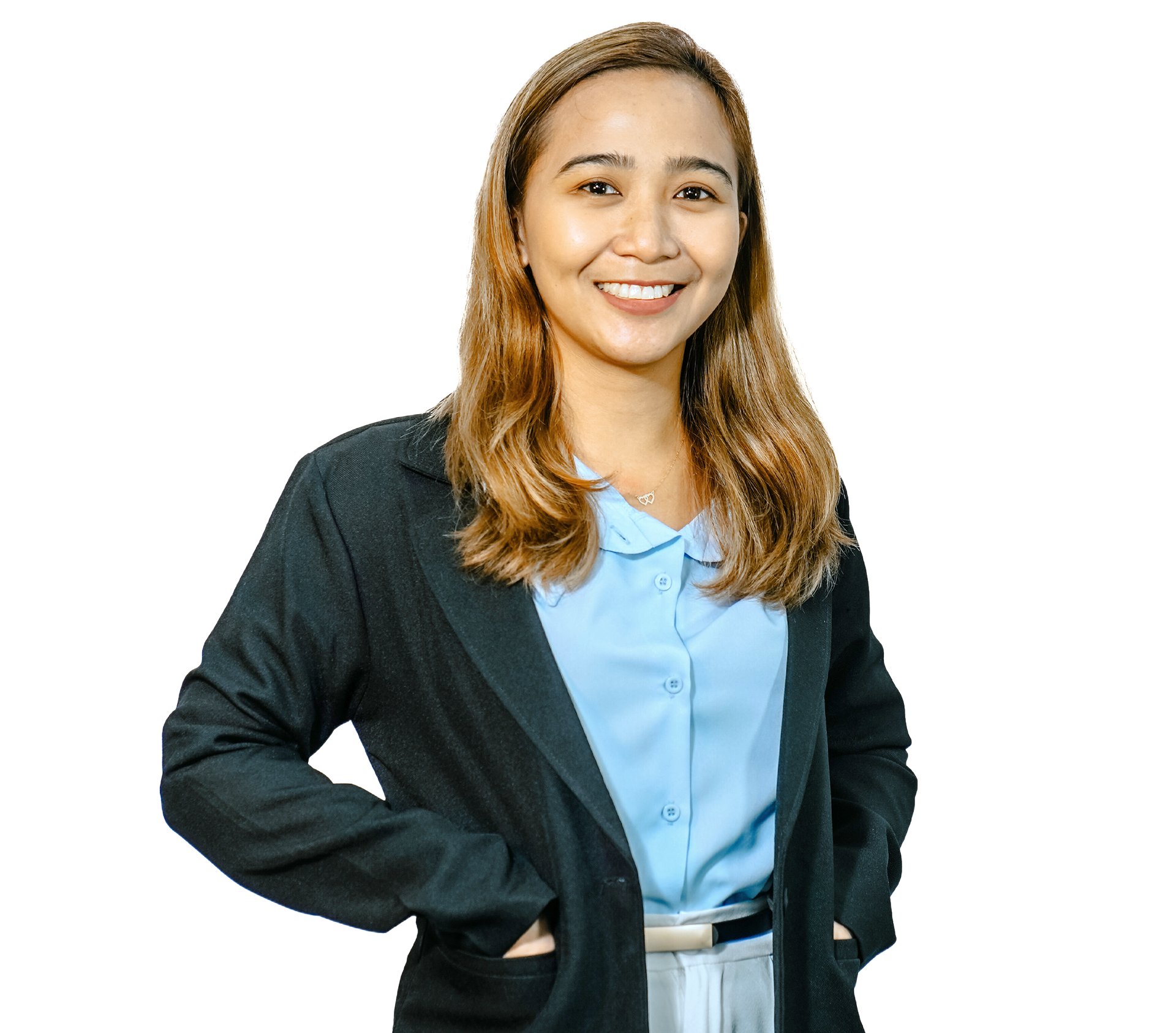 A person with long hair smiles, wearing a green blazer over a light blue collared shirt, hands resting on their hips.