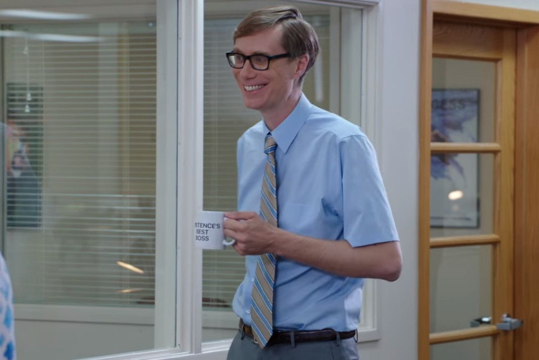 A man in a blue shirt and tie is holding a cup of coffee.