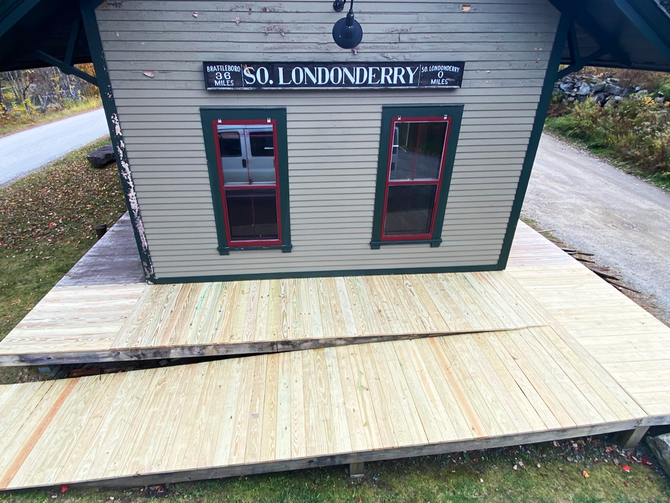A small building with a sign that says South Londonderry Depot and a fresh new deck built by JG Services
