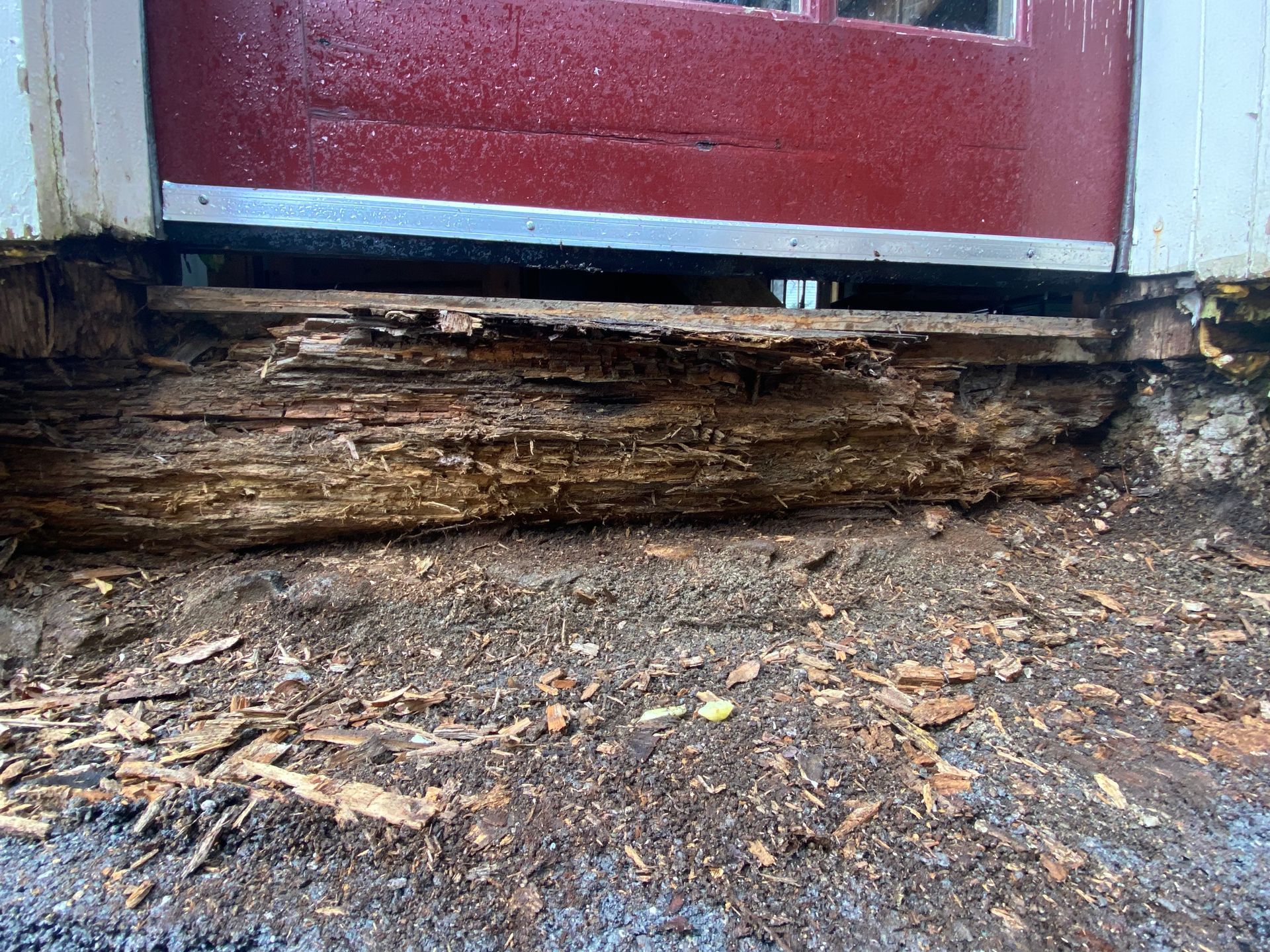 The BEFORE phot of wood rot under a door frame in desperate need of repair