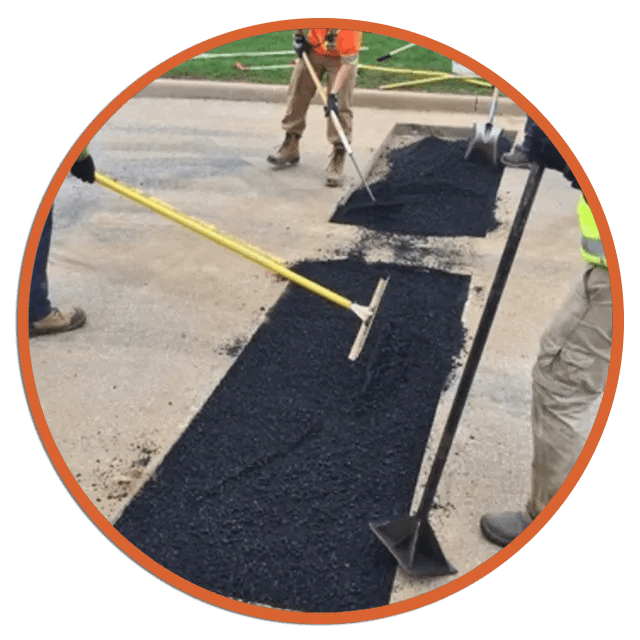 Workers paving asphalt on a road, using rakes and shovels.