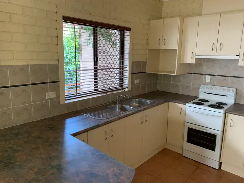 An empty kitchen with white cabinets and a stove