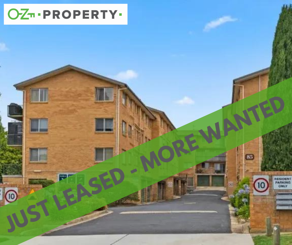 A brick apartment building with a green banner that says just leased more wanted