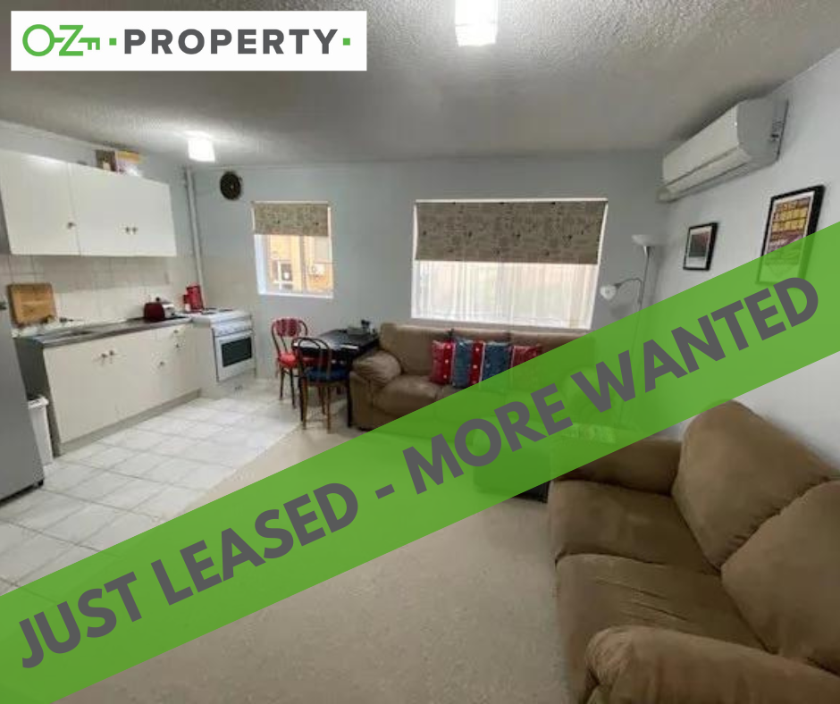 A living room with a couch and a sign that says just leased more wanted