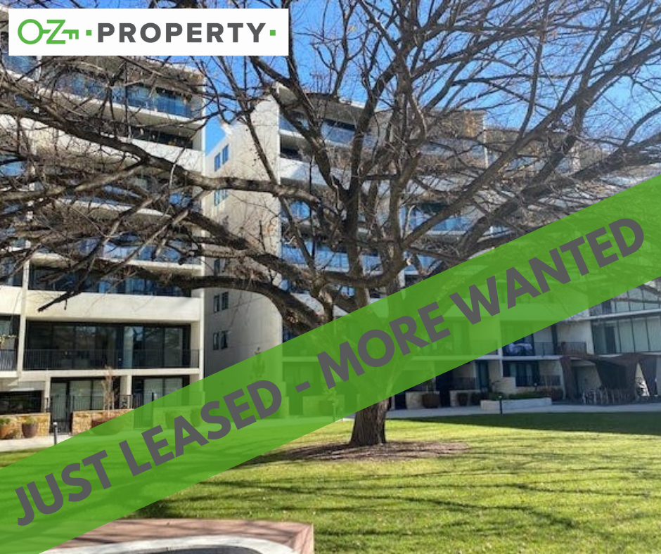 A building with a tree in front of it and a sign that says just leased - more wanted