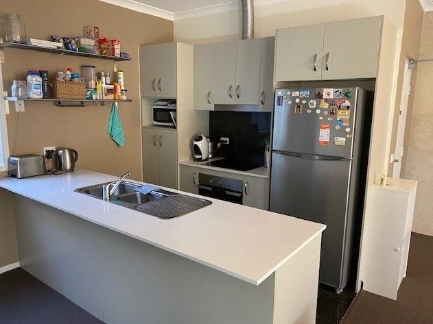 A kitchen with a refrigerator , sink , stove and microwave.