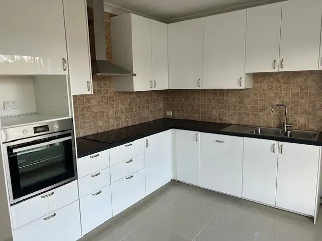 A kitchen with white cabinets and black counter tops