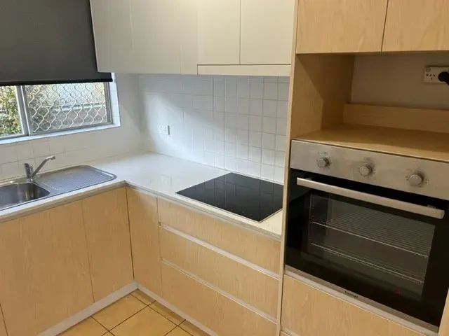 A kitchen with a stove , sink , and oven.