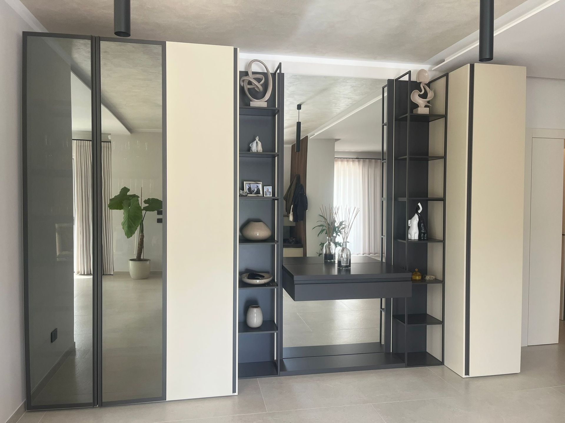 Zona trucco moderna con armadietti a specchio, mensole e lavabo in una stanza luminosa