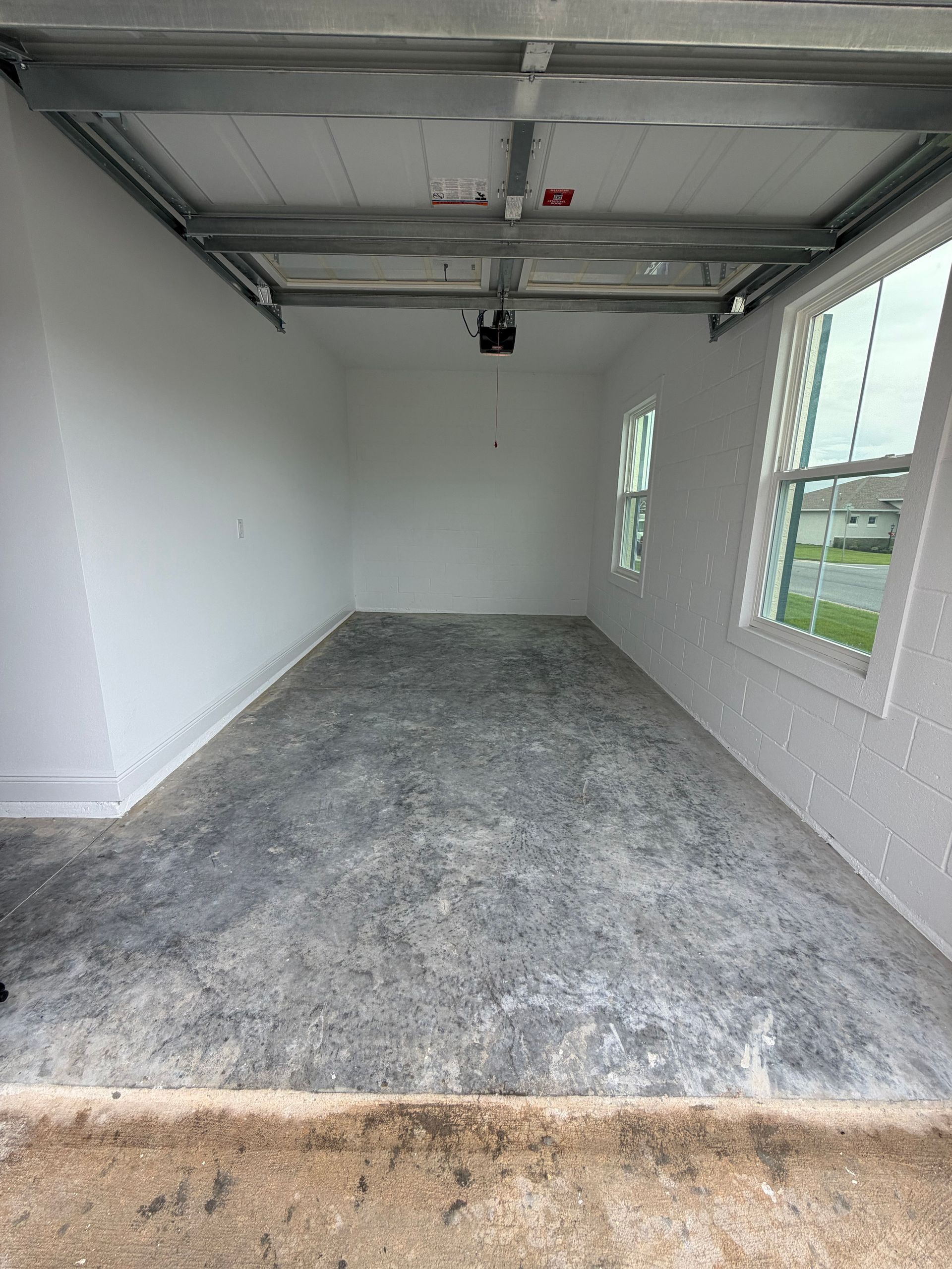 Empty detached garage with gray carpet and white walls, viewed from the open doorway
