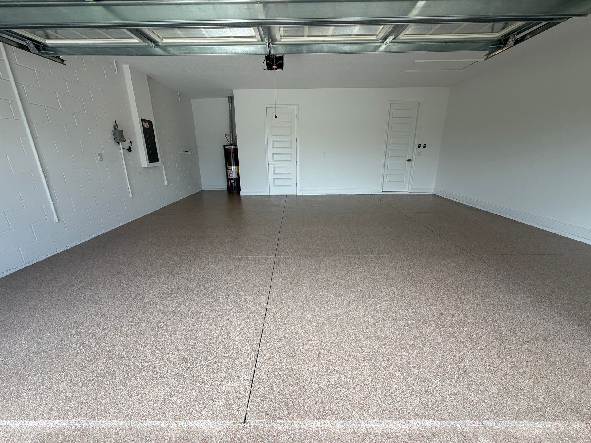 Empty garage interior with white walls, concrete floor, and open overhead door frame