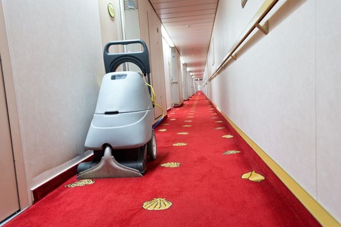 Red-carpet hallway with a floor-cleaning machine centered in the corridor.