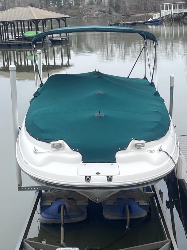 A red boat is sitting on a dock next to a blue jet ski