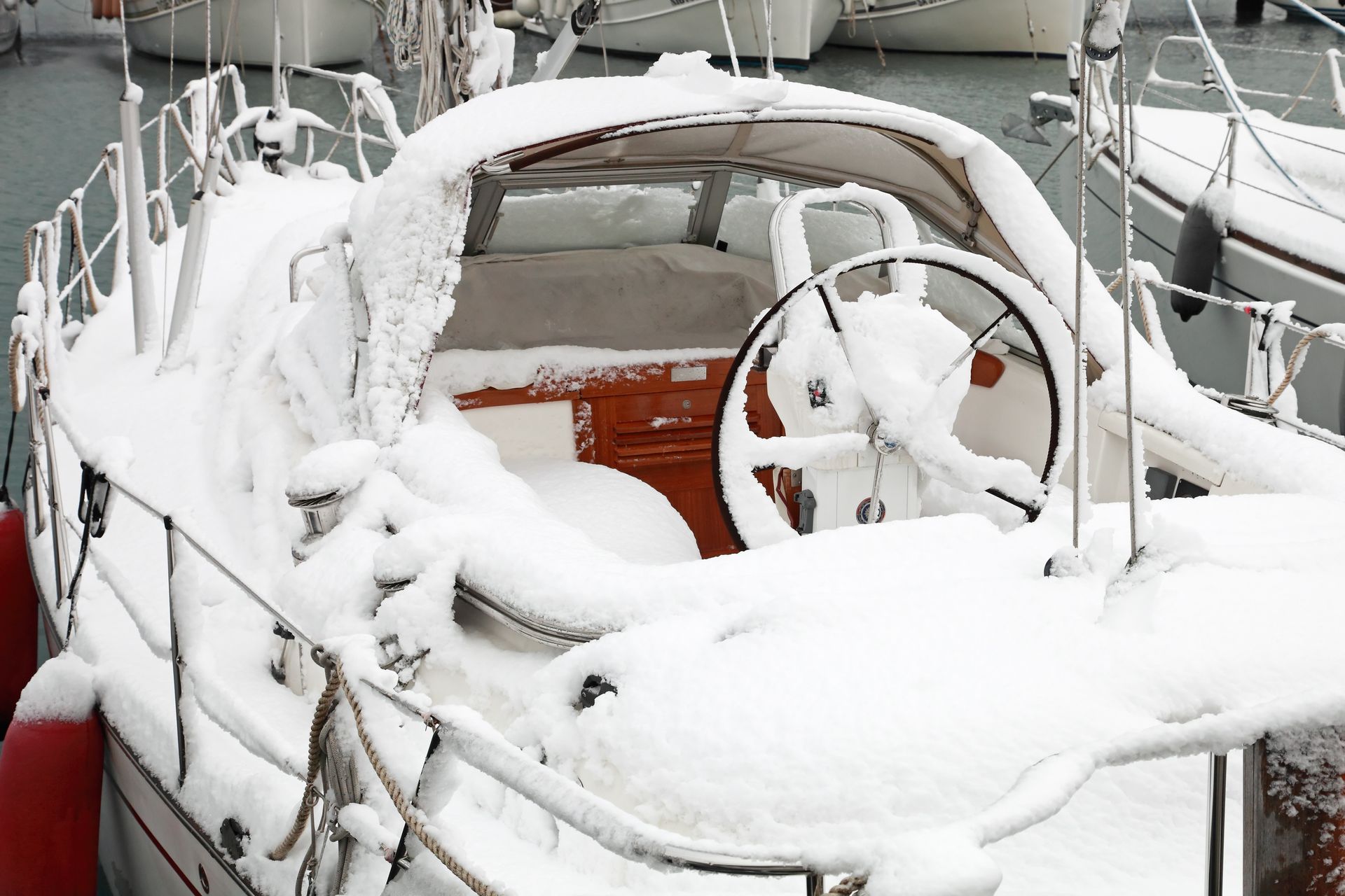 A boat is covered in snow and has a steering wheel