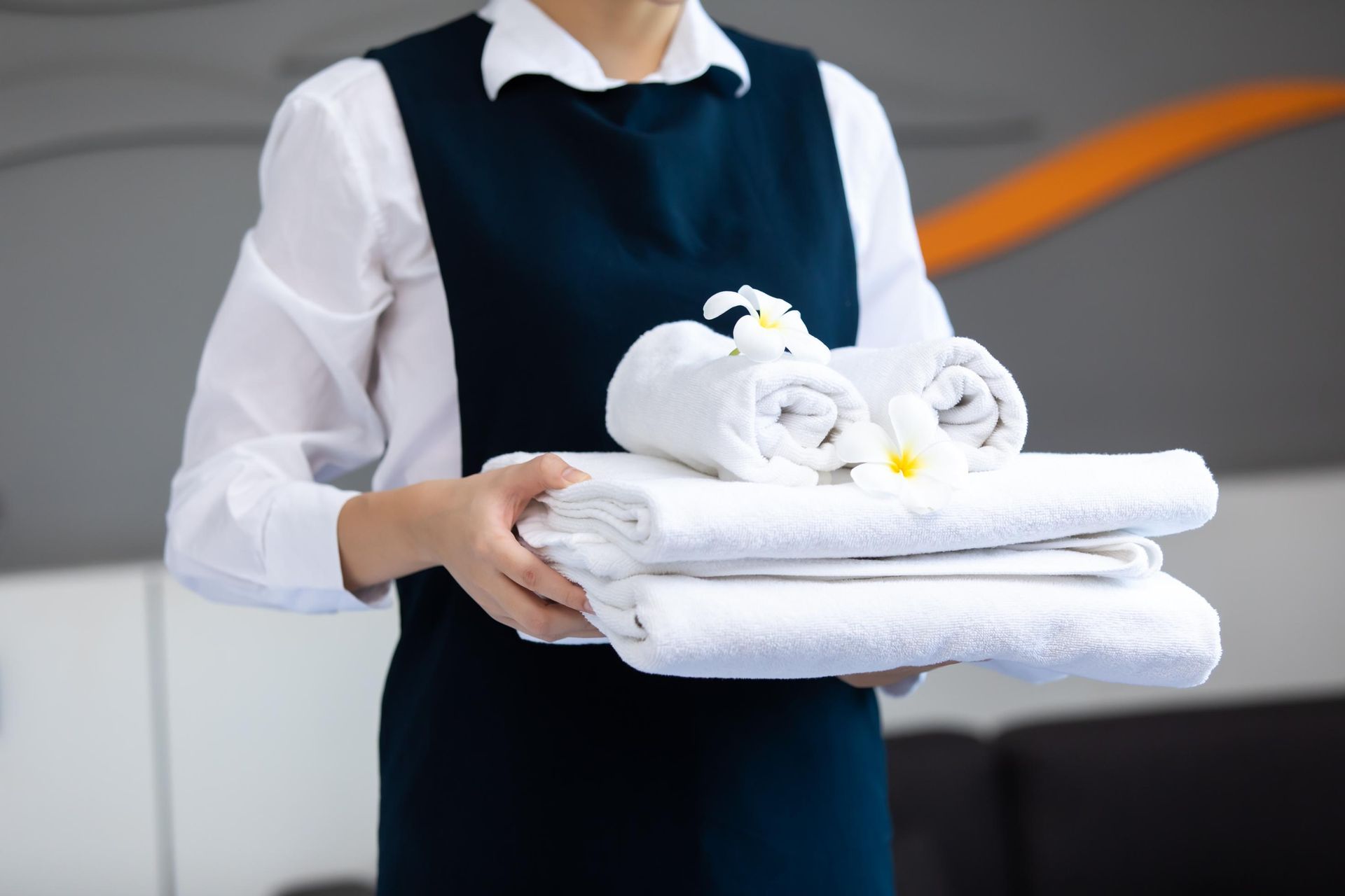Person holding folded white towels and bathrobes in a hotel setting